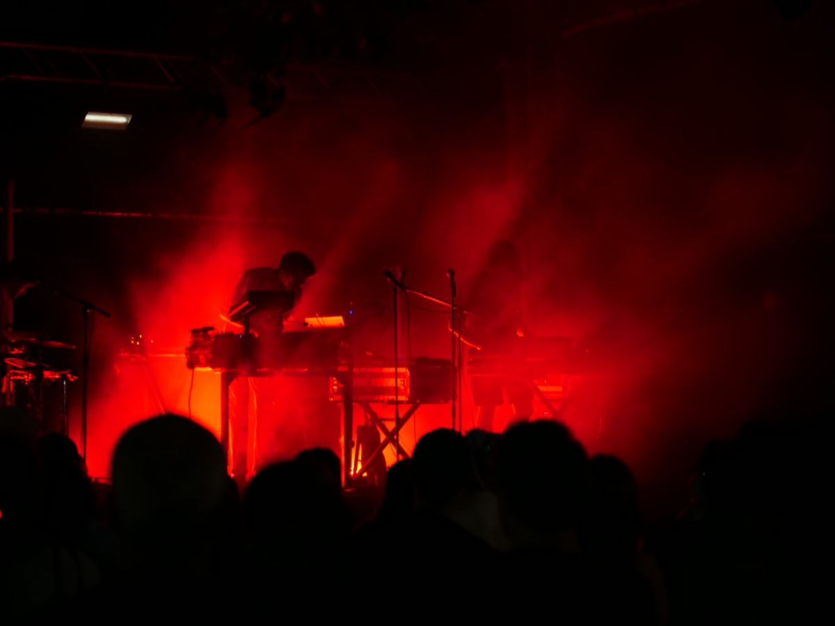 Palco de show de heavy metal tomado por fumaça e luz vermelha, clima teatral