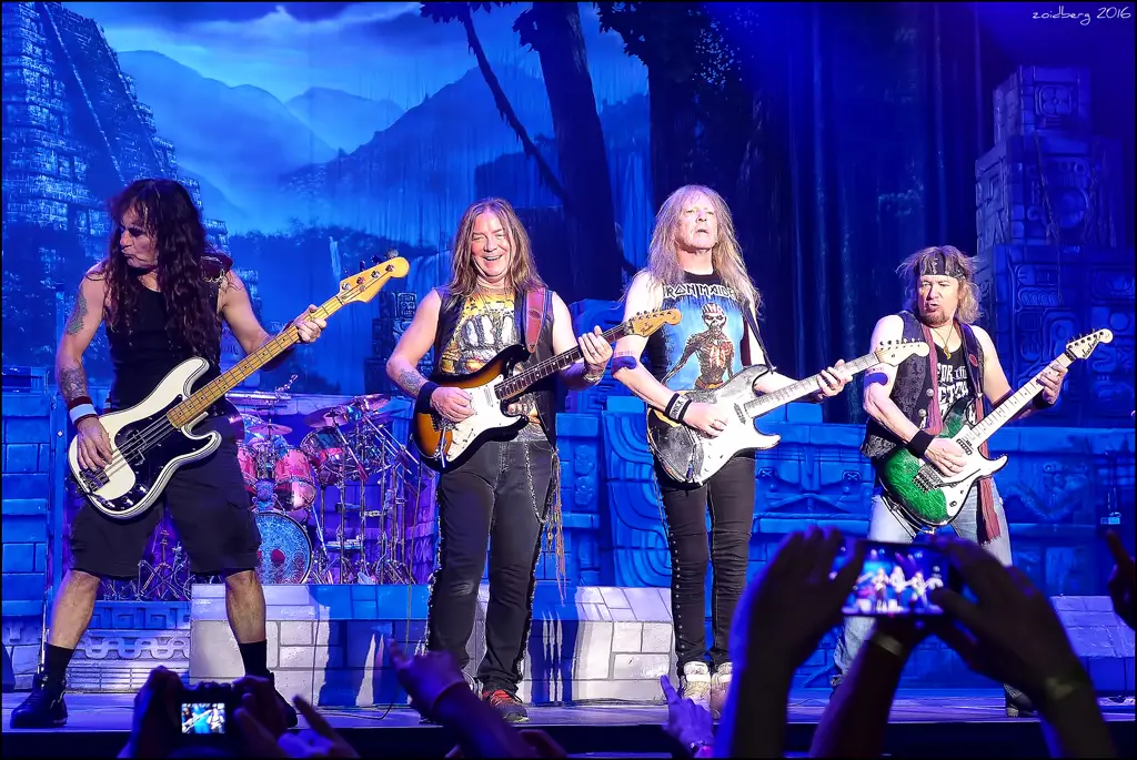 Iron Maiden ao vivo em Madri, 2016, baixista e três guitarristas no palco com cenário maia