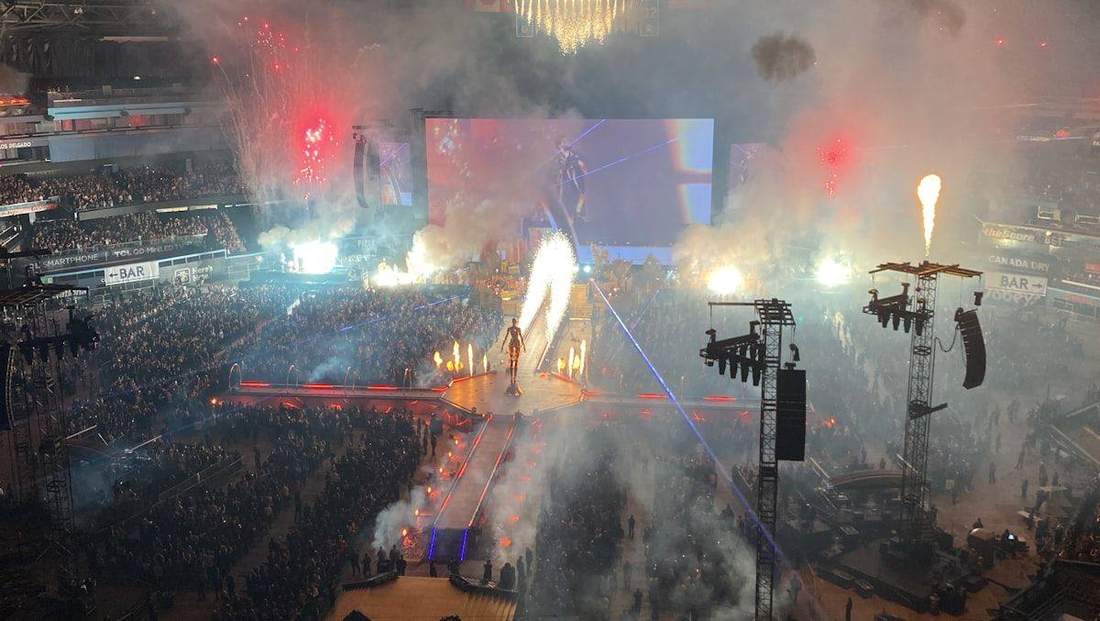 Palco de show com pirotecnia e público à noite, clima de show de R&B/pop
